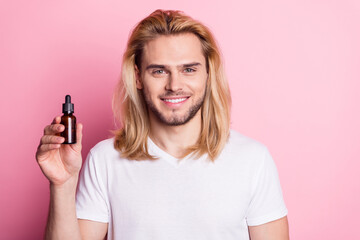 Photo of charming young happy man hold hands serum haircare isolated on pastel pink color background