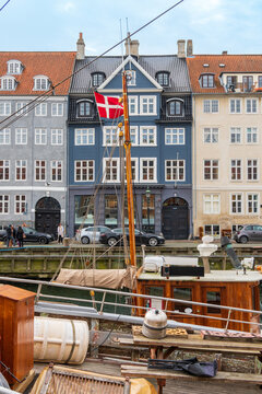Copenhagen, Denmark - October 1, 2021: Detail of the facade of a house in Nyhavn with the Danish flag hoisted to the mast of a boat 