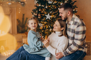 Family with little daughter together by the christmas tree