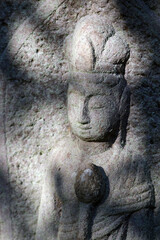 Tombstone decorated by merciful goddess stone sculpture. 穏やかな顔立ちの墓石に彫られた観音様。