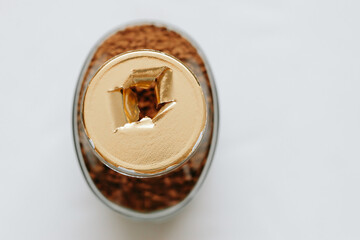 Top view of a glass jar of coffee without a lid, the gold-colored label is torn, the integrity of the packaging is broken, the background. Close-up.