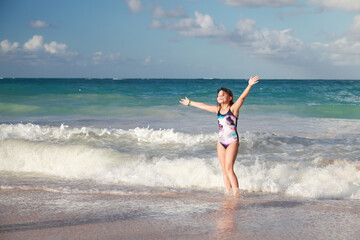 Happy little girl jumps in sore water at Bavaro beach