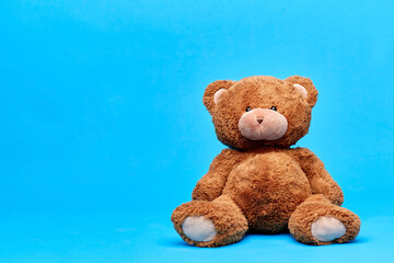 soft toys and childhood concept - brown teddy bear over blue background