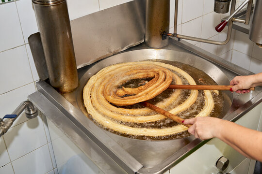 Cooking the dough for churros or porras in boiling hot oil on the stove. Typical Spanish breakfast