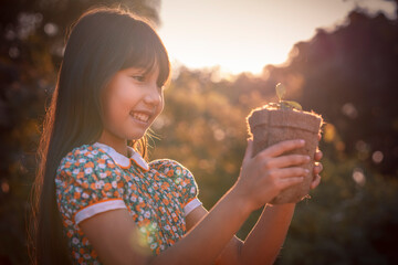 Young plant and girl. Little cute Girl give small plant to Sunshine.