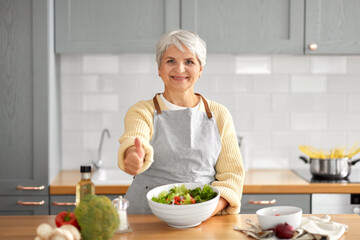 healthy eating, food cooking and culinary concept - happy smiling senior woman making vegetable...