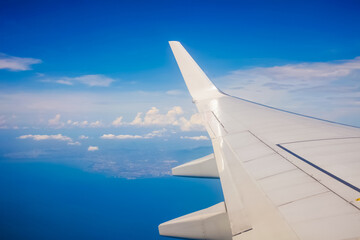 Obraz premium Plane window view with blue sky and clouds.