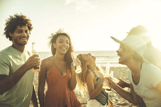 Group of friends having fun on the beach in Los angeles. Storytelling image of multiethnic people making a bone fire and barbeque at sunset. Spending a summer day in california