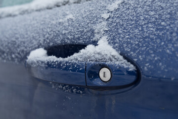 Snow-covered handle of the driver's door of the car. Concept of preparing the car for the winter. Warming up the castle.