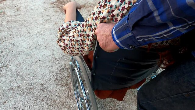detail of man's hands push his friend's wheelchair in the city - support, disability