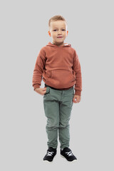 The boy is 5 years old. A child in jeans and a brown sweater. Isolated on a light gray background. Full height. Vertical.