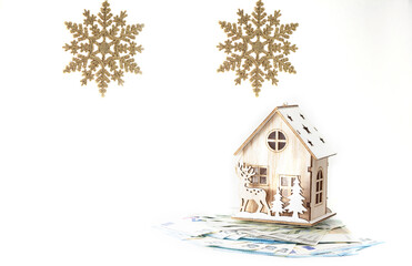 A Christmas house with money and two golden snowflakes.