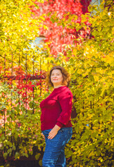 Chubby sunny woman in warm casual clothes in city park. Clothes for plus size ladies