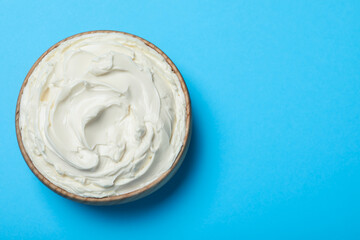 Bowl of tasty cream cheese on light blue background, top view. Space for text