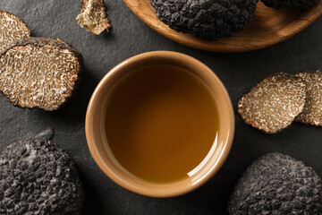 Bowl of truffle oil on slate table, flat lay
