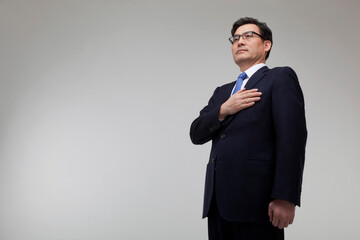 Middle-aged businessman wearing a suit and putting his hands on his chest to express his patriotism
