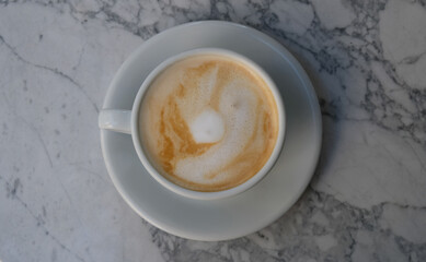 White mugs of cappuccino or latte decorated with foam on marble table background in Coffee shop. Morning coffee for couple in love. Top view. 