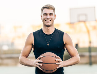Caucasian athletic man holding a basketball outdoors