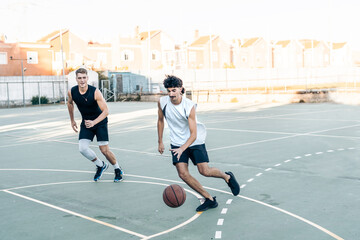 Two man running while playing basketball in an outdoor court