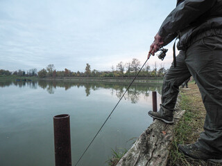 Caucasian man catching a fish with a fishing rod at the lake