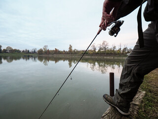 Caucasian man catching a fish with a fishing rod at the lake