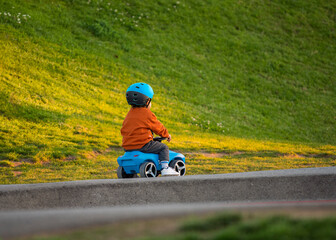 Child in helmet riding a toy car alone on the playground