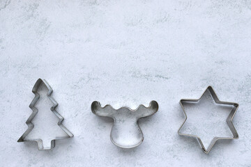 Christmas cookie cutters in star, christmas tree, deer shape on gray concrete background with copy space. Christmas frame, border, background
