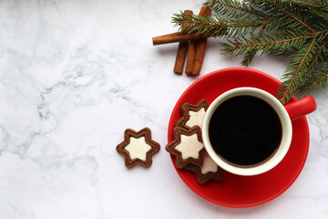 Obraz na płótnie Canvas Cup of coffee with star shaped cookies, cinnamon sticks and christmas decorations on white marble table. Christmas background. Top view, copy space. Flat lay winter holidays composition
