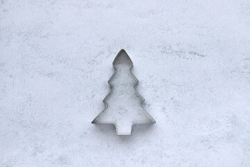 Cookie cutter in christmas tree shape on gray concrete background with copy space. Christmas background
