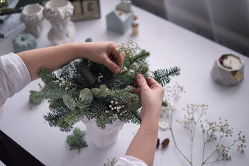 woman decorates a Christmas arrangement. Hands close-up. The new year celebration. Flower shop. Table decorations, floral composition.