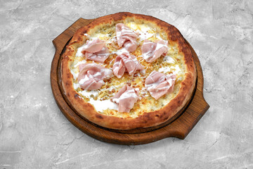 Fresh pizza with ham and pineapple on stone table in restaurant.