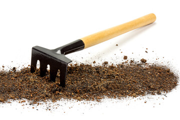 Pile heap of soil with small garden rake tools isolated on a white background