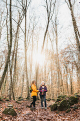 Fototapeta premium Two senior female friends hiking together through the forest in autumn