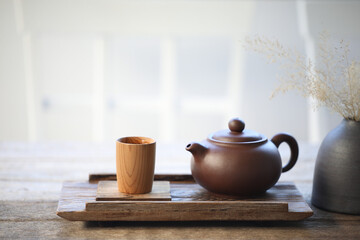 Pottery tea pot and bamboo tea cup on wooden tray