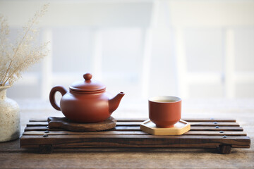 Pottery tea pot and tea cup on wooden tray