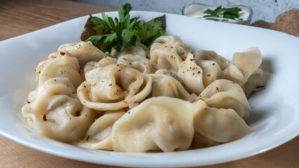 Boiled meat dumplings. Close-up view of russian boiled pelmeni on white plate.