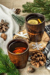 Hot black tea and lemon with winter decor. Cozy sweater, fir tree branches, nuts, snowflakes