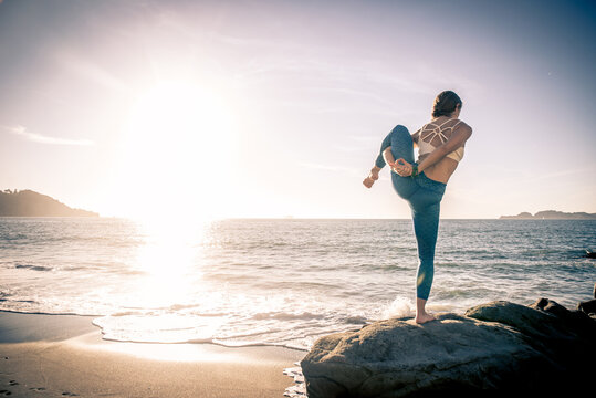 Image of a beautiful young woman making yoga training and meditation on the beach and rocks at baker beach in san francisco. 