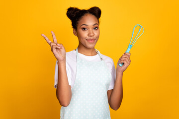 Photo of young pretty african woman cooking bake show fingers peace cool v-symbol isolated over...