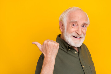 Profile photo of cheerful aged person indicate thumb empty space isolated on yellow color background