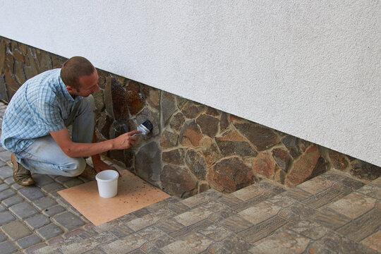 varnish the stone on the house,stone with foundation man applies varnish with a brush