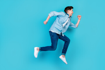 Fototapeta na wymiar Full body profile side photo of young guy jump run rush look empty space isolated over blue color background