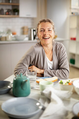 Beautiful woman enjoying in breakfast. Happy young woman eating sandwich at home.