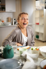 Beautiful woman enjoying in breakfast. Happy young woman eating sandwich at home.