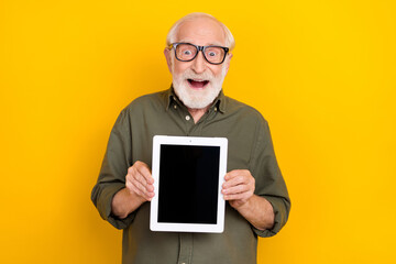 Portrait of astonished person demonstrate empty space tablet display proposition isolated on yellow...
