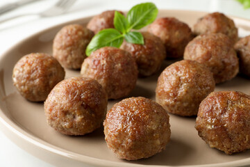Tasty cooked meatballs with basil on plate, closeup