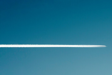 Expressive underlining. A white trail in the sky from a flying plane in freezing weather. Blue sky....