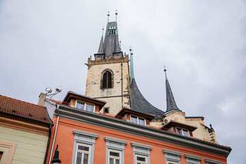 Louny, Czech Republic, 19 September 2021: Medieval catholic stone church of St. Nicholas with gothic high spire clock tower in autumn day, Narrow picturesque street in historic city center, arches