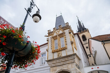 Louny, Czech Republic, 19 September 2021: Regional Museum at House of the Falcons of the Mor, Historical town building with gothic facade, spire tower of St. Nicholas church at autumn sunny day © AnnaRudnitskaya