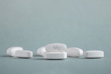 Tablets , vitamins with the abbreviation Mg ( magnesia, macro element magnesium ) on a light background. Copy space. - obrazy, fototapety, plakaty